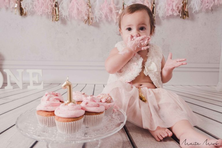 Fotografía smash cake de una bebé celebrando su primer año con pastelitos